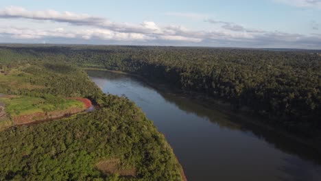 Peaceful-drone-flight-over-Iguazu-River-surrounded-by-dense-tropical-amazon-Rainforest-at-sunset