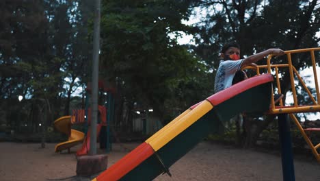 An-adventurous-young-boy-fearless-as-he-slides-backwards-down-a-slide-at-a-park-playground-enjoying-the-evening-as-he-plays-outdoors