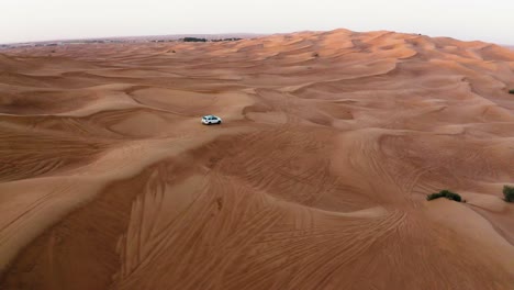 Aerial-Drone-Shot-Of-A-White-4x4-Car-In-The-Desert-Sand