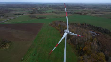Aerial-shot-of-rotating-wind-turbine-with-red-edges-for-renewable-electric-power-production-in-a-field