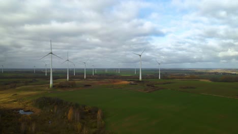 Luftaufnahme-Von-Rotierenden-Windmühlen-Der-Gruppe-In-Einem-Windpark-Zur-Erzeugung-Erneuerbarer-Energie-In-Einer-Landschaft-In-4k