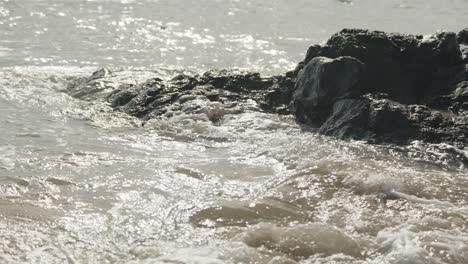 Wellen,-Die-An-Einem-Warmen-Sommertag-Gegen-Alten-Vulkanischen-Schwarzen-Felsen-Krachen,-Abstrakter-Hintergrund