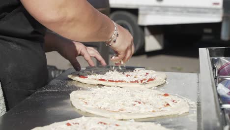 Woman-spreading-fresh-mozzarella-cheese-on-pizza-dough-outdoors,-slow-motion