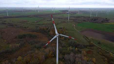 Aerial-shot-of-multiple-spinning-windmills-for-renewable-electric-power-production-in-a-wide-rural-area-on-a-cloudy-day