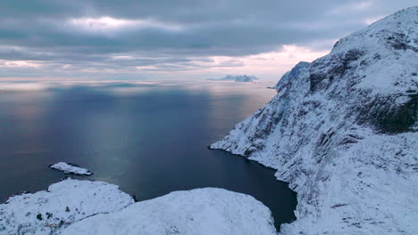 Lofoten-islands-extreme-frozen-mountain-and-wintry-blue-ocean-landscape-aerial-view-slowly-moving-right