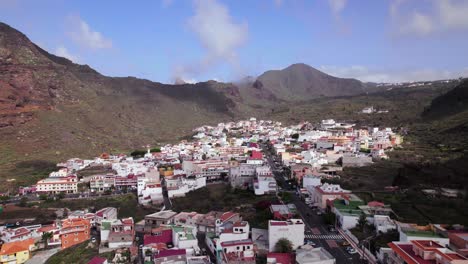 Aerial-rising-panoramic-view-of-a-town-in-Tenerife,-green-hill-landscape