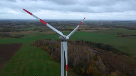 Aerial-shot-of-rotating-wind-turbine-with-red-edges-for-renewable-electric-power-production-in-a-field-in-4k