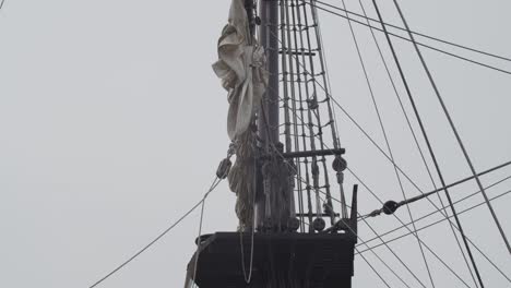 Galleon-Andalucia-replica-ship-detail-tilt-shot-of-the-mainmast,-roundhouse-and-sails-while-docked-in-Valencia-in-slow-motion-60fps