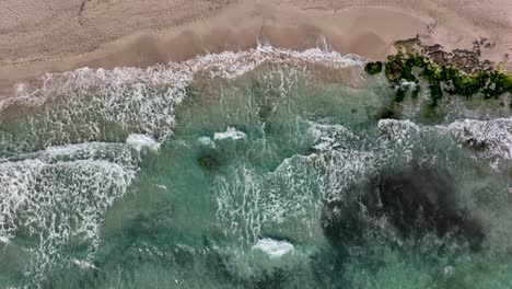 Top-down-view-of-waves-hitting-beach-in-slowmotion,-Cala-Millor