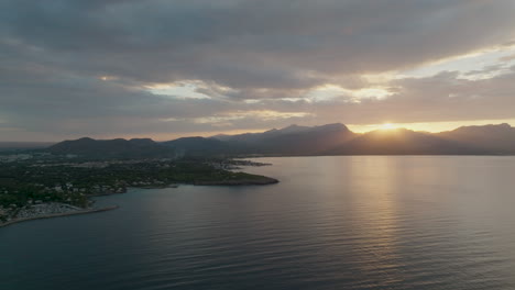 Drohnenflug-An-Der-Küste-Von-Mallorca-Mit-Blick-Auf-Die-Gegend-Von-Bahia-De-Pollenca-Mit-Spektakulärem-Sonnenuntergang-über-Den-Bergen