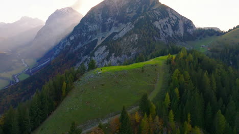 Aerial-view-orbiting-Austrian-forested-alpine-hillside-as-surays-shine-through-Tyrol-mountain-landscape