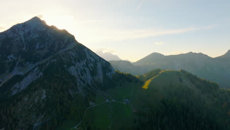 Sunlight-emerging-behind-Tyrol-mountain-peaks,-Austria-aerial-view-across-untouched-wilderness