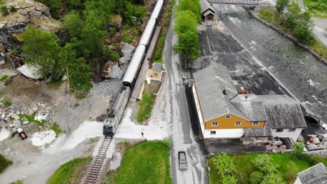 Aerial:-Flåm-train-going-through-a-valley-among-green-meadows