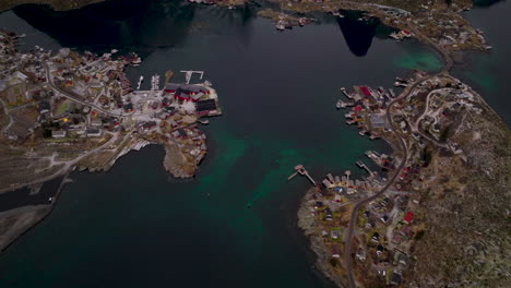 Reine-top-down-aerial-view-over-arctic-Lofoten-Moskenes-municipality-fishing-village-and-snow-capped-mountain-landscape