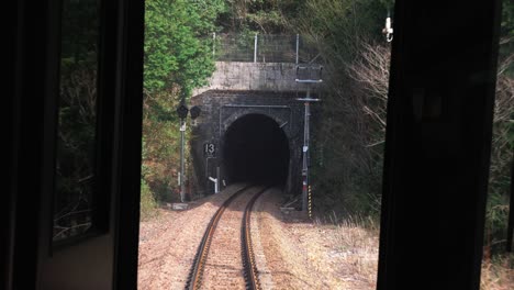Saliendo-Del-Túnel-Y-Cruzando-El-Puente-En-Zona-Montañosa,-Viendo-Desde-La-Puerta-Trasera-Del-Tren
