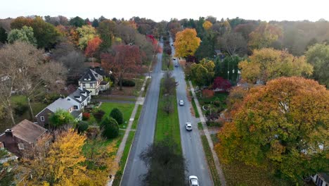 Rising-aerial-of-cars-driving-through-upscale-American-suburbia-during-autumn