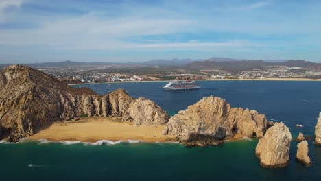 Aerial-view-away-from-the-lovers-beach-with-a-cruise-liner-in-the-background-in-Cabo-San-Lucas,-Mexico---pull-back,-drone-shot