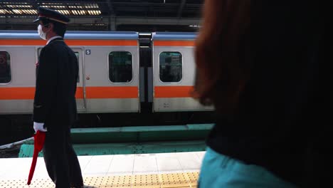 Tren-Que-Llega-Y-Trabajador-Que-Controla-La-Estación-En-Japón,-4k