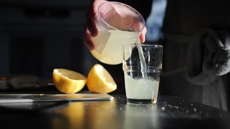 Person-with-robe-pouring-fresh-lemon-juice-into-glass,-early-morning-healthy-routine