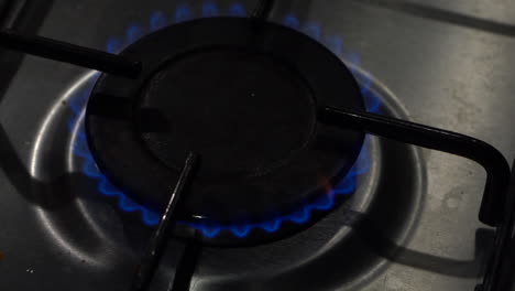 Close-up-high-angle-burner-on-gas-stove-ignites-into-bright-blue-flame