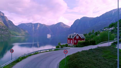 Picturesque-villa-on-the-edge-of-Aurlandsfjord-in-Norway-with-a-cruise-ship-on-the-water-beneath-the-mountains