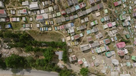 Top-down-aerial-footage-that-is-sped-up-that-crosses-over-a-road-with-a-motorcycle-on-it-and-moves-over-a-colorful-cemetery-in-the-city-of-Chichicastenango,-Guatemala