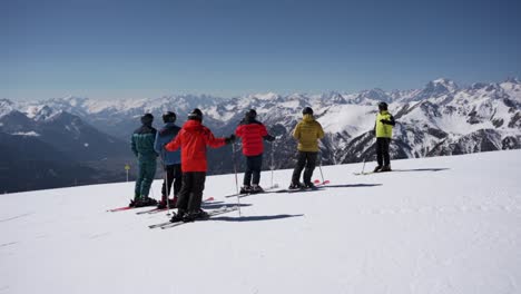 Skiers-on-top-of-the-mountain-before-skiing-down-looking-at-the-mountain-panorama-in-winter
