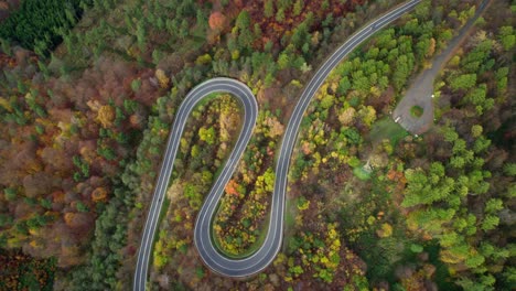 Car-and-a-motorcycle-driving-in-a-wonderful-curvy-road-in-the-mountains-surrounded-by-a-beautiful-autumn-forest-in-the-nature