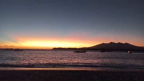 Wunderschöner-Sonnenaufgang-Am-Strand-Von-Gili-Trawangan-Am-Morgen-Mit-Einem-Boot-Und-Einem-Berg