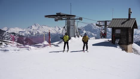 Skiers-leaving-the-ski-lift-reaching-the-top-of-the-mountain-and-beginning-to-ski