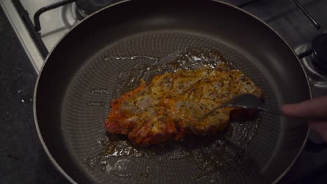 High-angle-view:-Beef-chuck-steak-is-flipped-in-hot-fry-pan-on-stove