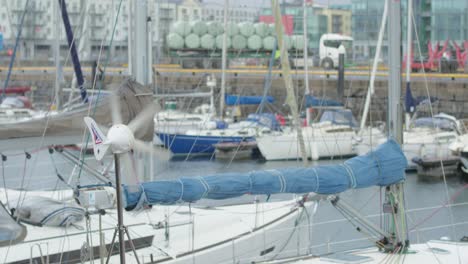 Blick-Auf-Die-Docks-Der-Stadt-Galway-Mit-Festgemachten-Booten,-Während-Sich-Eine-Windfahne-Im-Wehenden-Wind-Dreht
