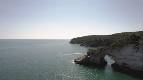 Drone-flying-in-large-circulair-motion-around-a-large-coastal-arch-in-the-sea-of-Gargano-National-Park-in-Italy-4k