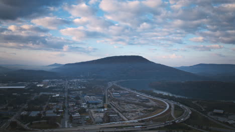 Aerial-hyperlapse-timelapse-focused-on-Lookout-Mountain-during-the-sunrise-with-clouds-in-the-sky,-boats-in-the-Tennessee-River-and-traffic-on-the-highway