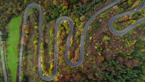 Aerial-from-top-to-down-over-a-winding-mountain-road-surrounded-by-a-forest-with-autumn-trees-in-the-mountains-of-bieszczady-in-Poland,-europe