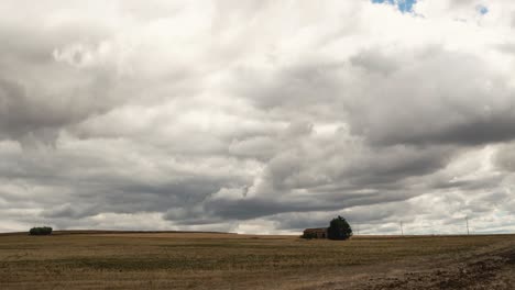 Zeitraffer-Von-Schweren-Wolken,-Die-Sich-über-Ein-Farmfeld-Mit-Einem-Kleinen-Malerischen-Haus-Darauf-In-Süditalien-In-4k-Bewegen
