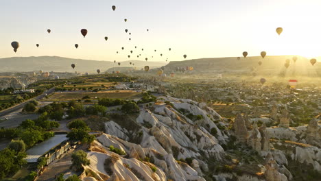 Göreme-Turkey-Aerial-v62-flyover-plateau-field-capturing-scenery-of-volcanic-rock-formations-and-hot-air-balloons-high-up-in-the-sky-at-sunrise-golden-hours---Shot-with-Mavic-3-Cine---July-2022