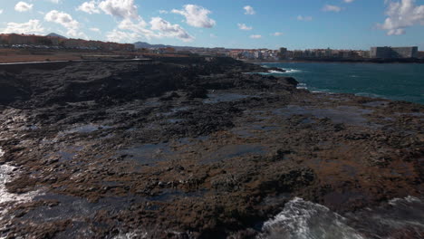 Drohne-Bewegt-Sich-Vorwärts-über-Den-Ozean-Im-Vordergrund-Ist-Gran-Canaria-Sea-Cliff-Wellen-Fließen-über-Den-Steinstrand-Von-Gran-Canaria