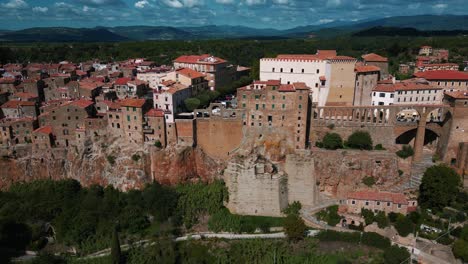 Pitigliano,-a-famous-Tuscany-city-on-Etruscan-tufa-rocks-with-old-houses-and-buildings-near-beautiful-Siena-and-Florence,-Italy,-close-to-wine-and-vinery-area,-seen-from-above-by-drone-as-aerial-view