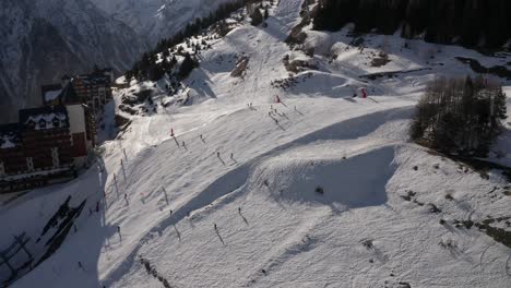 Drone-aerial-view-of-skiers-skiing-on-a-slope-in-the-mountains-during-winter