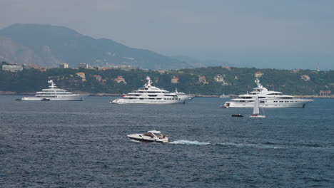 Teure-Yachten,-Die-In-Der-Bucht-Von-Monaco-Verankert-Sind,-Mit-Vorbeifahrendem-Motorboot-Im-Vordergrund
