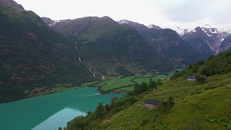 Yrisetra-small-cottages-far-up-in-Olden-mountainside-with-briksdal-glacier-in-mountain-background---Stunning-aerial-from-amazing-hillside-viewpoint-in-popular-destination-in-Nordfjord
