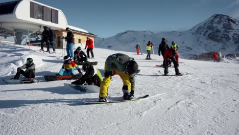Snowboarders-fastening-boots-before-going-down-the-slope-in-the-winter