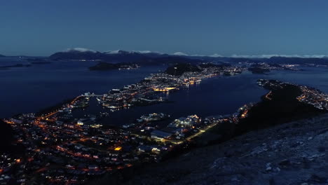 Ålesund,-a-village-port-in-Møre-og-Romsdal-County-of-Norway-nighttime-aerial-view-with-snow-on-the-distant-mountains