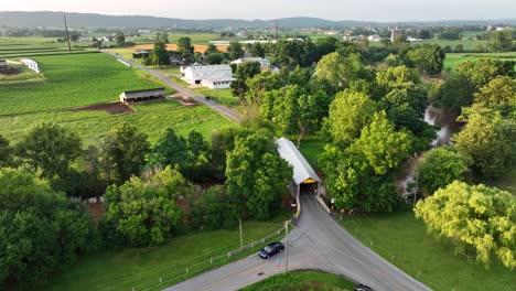 A-beautiful-aerial-view-of-a-covered-bridge-surrounded-by-lush-green-farmland-and-farms