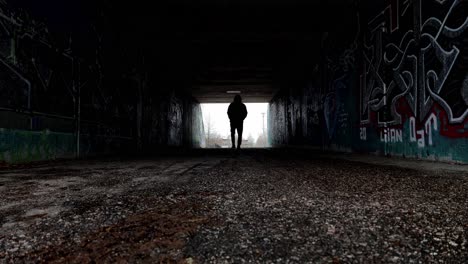 Silhouette-of-a-man-walking-in-a-dark-tunnel