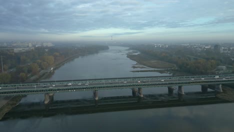 Luftaufnahme-Des-Morgendlichen-Warschaus-Mit-Der-Gdanski-brücke-Im-Vordergrund-Und-Dem-Dominierenden-Kohlekraftwerk-Im-Hintergrund-Kamera,-Die-Sich-Der-Brücke-Nähert-Und-Absteigt