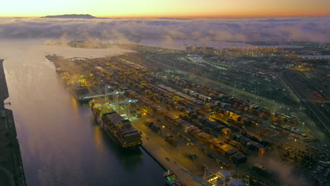 Nighttime-sunset-view-of-the-Port-of-Oakland-and-the-waterways-along-the-harbor---aerial-reveal