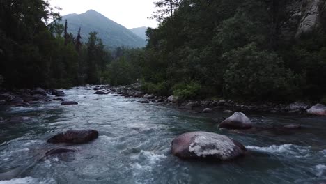 Río-Que-Corre-En-Las-Montañas-De-Alaska-Con-Rocas-Y-Bosques-Aledaños
