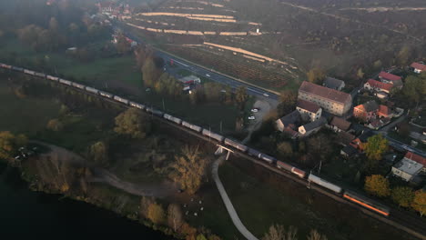 Train-driving-on-railway-along-Elbe-river-near-Melnik-city-in-Czech-Republic,-drone-evening-view